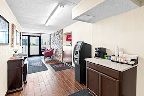 A hotel lobby with a reception desk, a coffee machine, and a self-service kiosk.