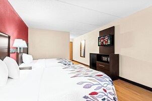 Habitación de hotel con cama, escritorio, televisor y microondas.