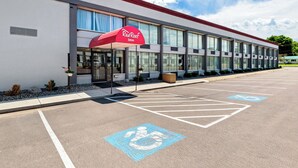 A Red Roof Inn with a parking lot, marked handicapped parking spaces, and a clear sky. - Red Roof Inn Cortland (Cortland)