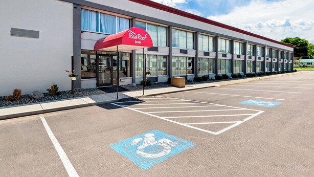A Red Roof Inn with a parking lot, marked handicapped parking spaces, and a clear sky. - Red Roof Inn Cortland (Cortland)