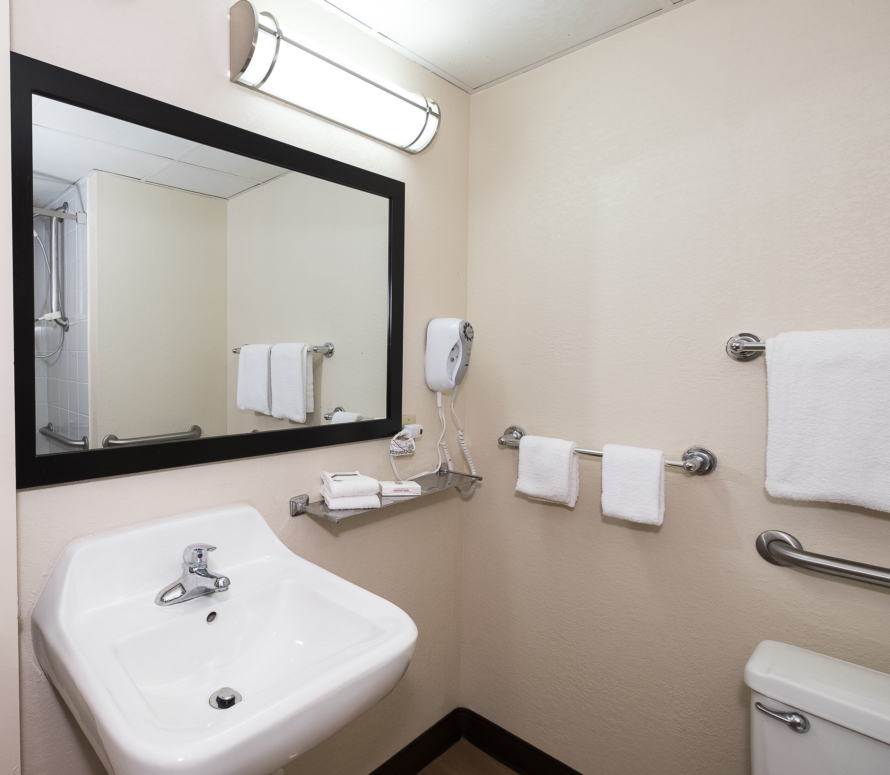 A bathroom with a white sink, a mirror, a towel rack, and a toilet.