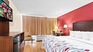 A hotel room with a bed, a desk, a chair, a television, and a window with curtains. - Red Roof Inn Cortland (Cortland)