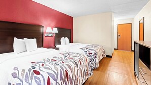 A hotel room with two beds, a television, and a bathroom door. - Red Roof Inn Cortland (Cortland)