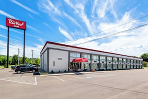 A RedRoof Inn building with a parking lot and a clear blue sky.