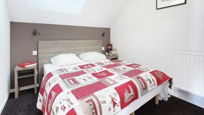 A bedroom with a bed, a nightstand, a teddy bear, a framed picture, and a window. - Apartment in French Alps with Heated Pool (La Salle les Alpes)
