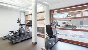 A gym with treadmills and an elliptical machine, large windows with a view of a snowy landscape and parked cars. - Apartment in French Alps with Heated Pool (La Salle les Alpes)