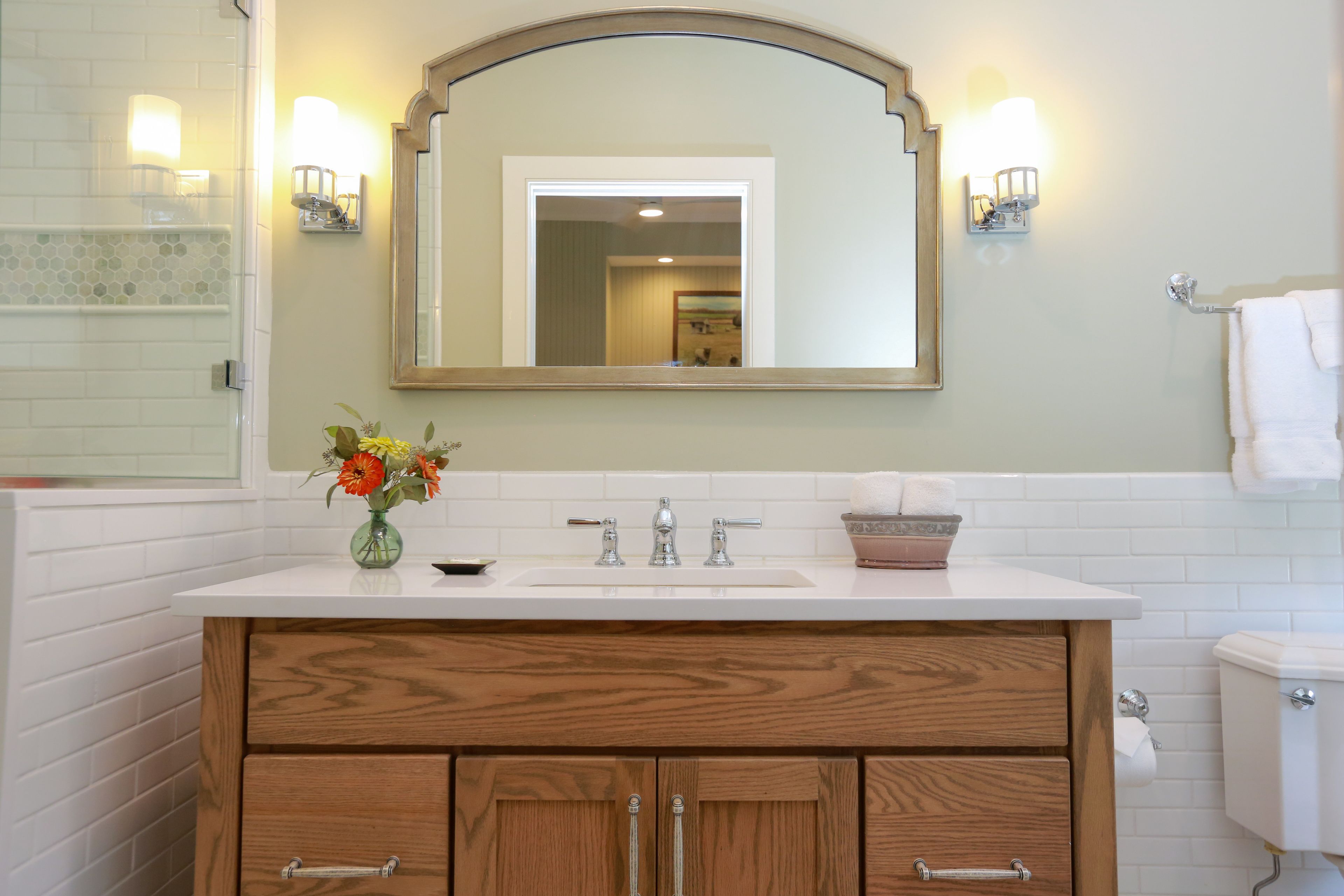 A bathroom with a white sink, wooden vanity, and a mirror above the sink.