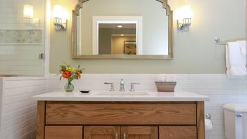 A bathroom with a white sink, wooden vanity, and a mirror above the sink.