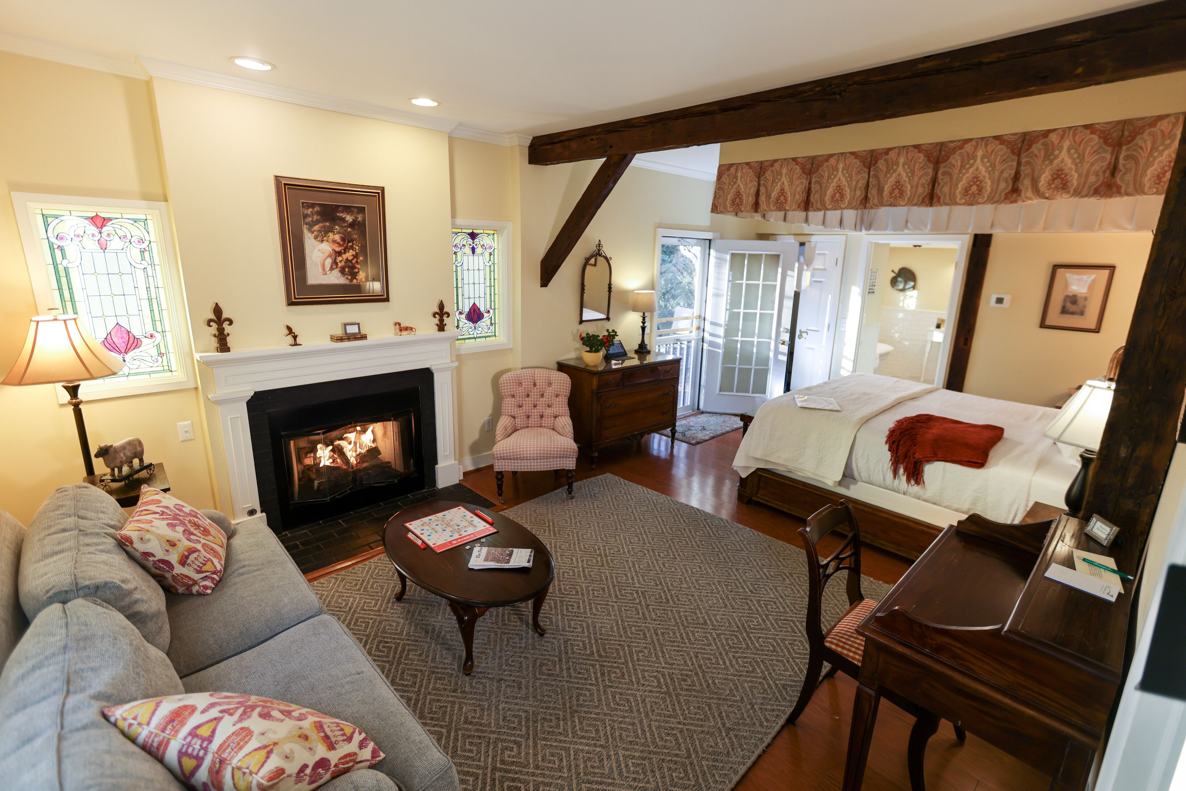 A cozy living room with a fireplace, a sofa, a dining table, and a bed.