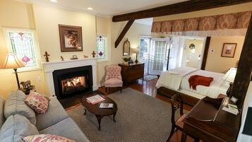 A cozy living room with a fireplace, a sofa, a dining table, and a bed.