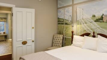 A bedroom with a large window, a bed with white linens, a chair, and a door leading to another room.