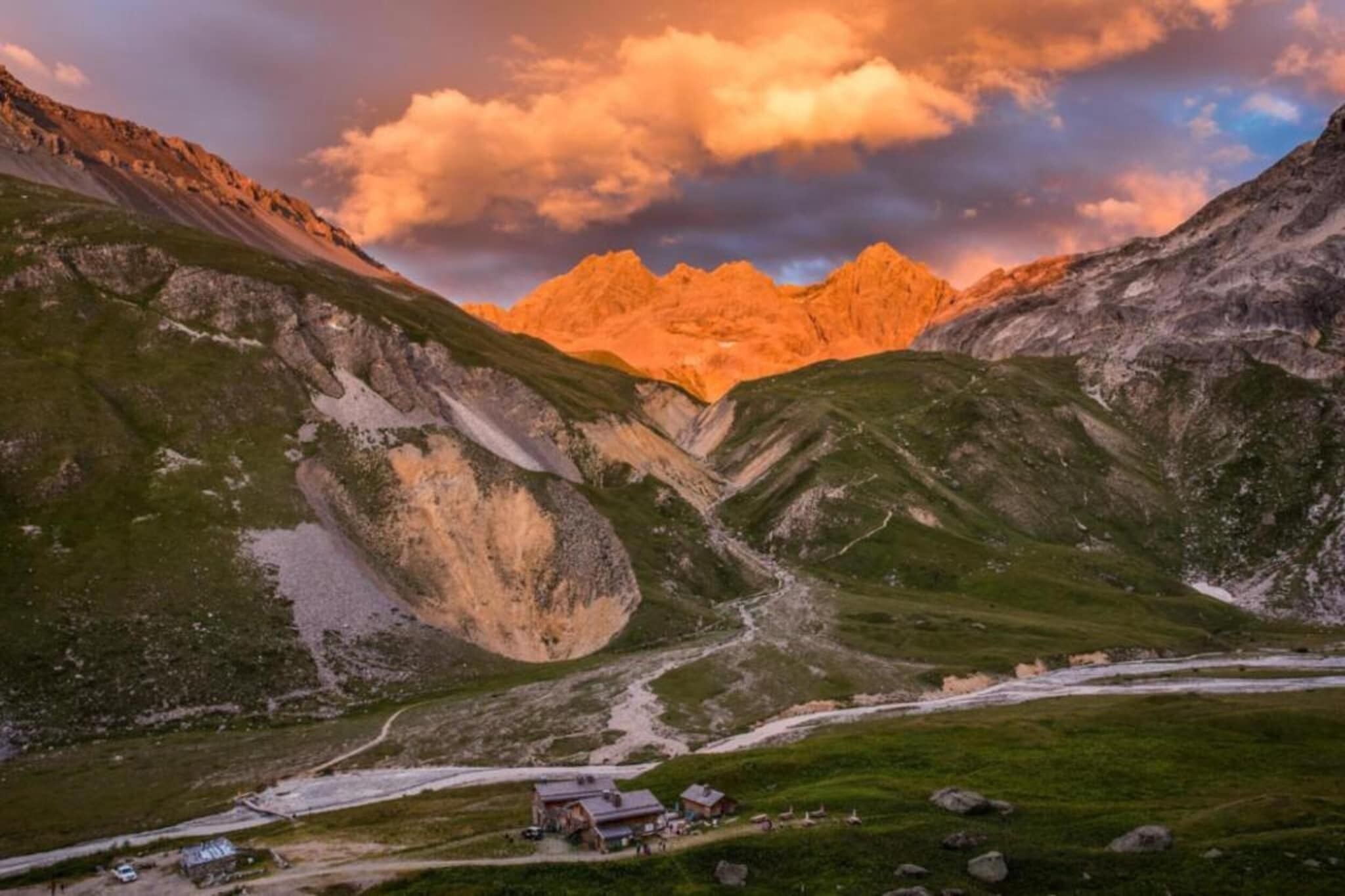 Paisaje montañoso con un pequeño asentamiento, que incluye una carretera y edificios.