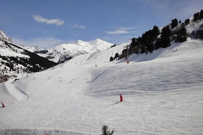 Une piste de ski enneigée, avec des remontées mécaniques et des arbres.