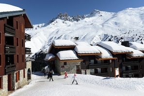 Un chalet de montagne enneigé, doté d’une architecture en bois, avec des pistes de ski en arrière-plan.