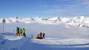 Eine verschneite Berglandschaft mit Skifahrern und einem roten Pfahl.