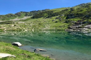 Un lago de montaña cristalino con costas rocosas y un primer plano cubierto de hierba.