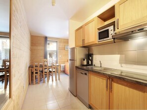 Une cuisine moderne avec des meubles en bois, un réfrigérateur en acier inoxydable, un four à micro-ondes et un lave-vaisselle.