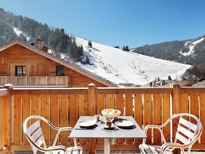 A wooden cabin with a balcony overlooking a snowy mountain.