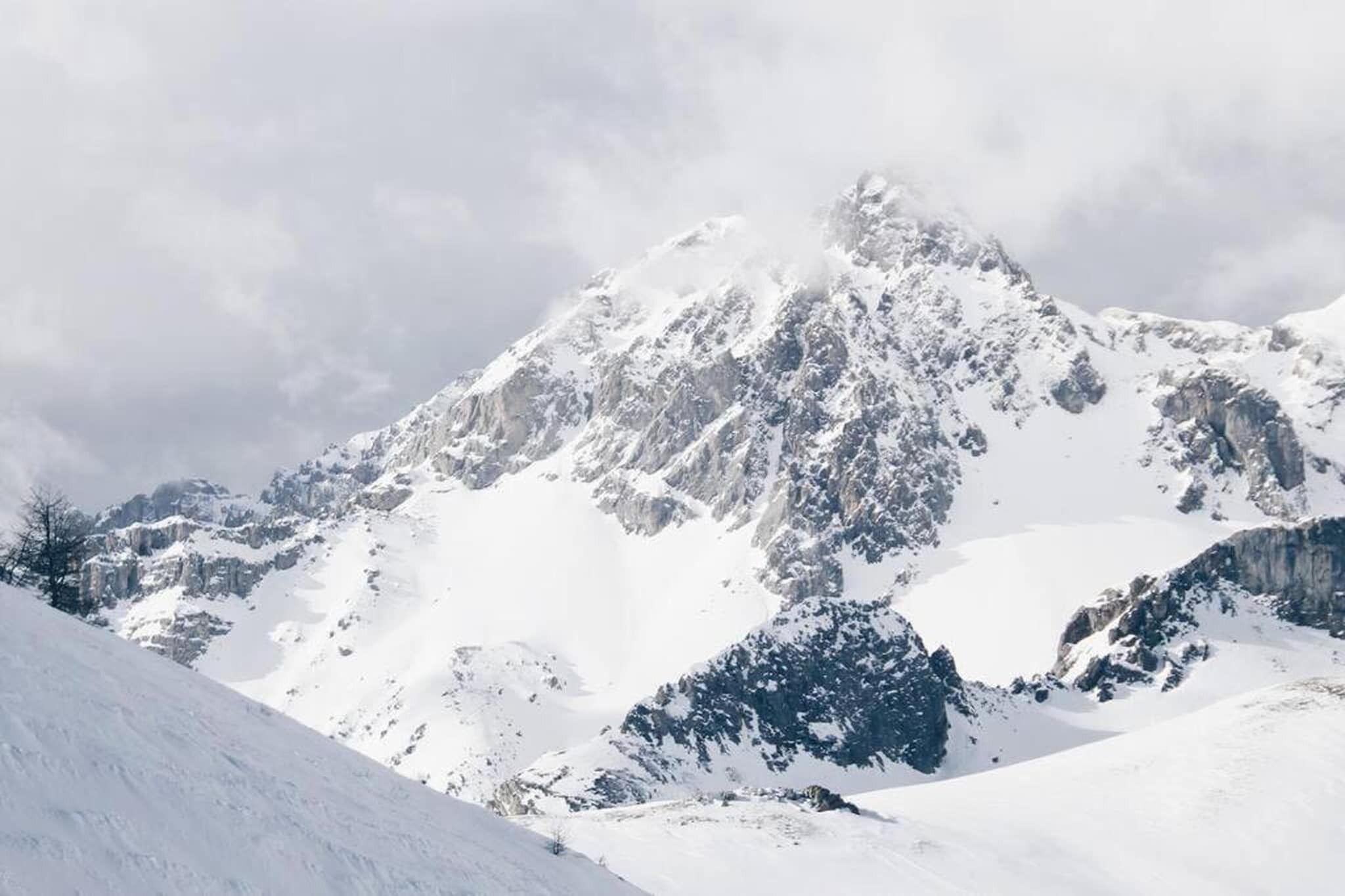 Ett snötäckt berg med ett kargt landskap och framträdande klippformationer.
