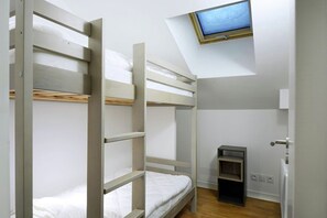 Ein Schlafraum mit Etagenbetten und einem kleinen Fernseher an der Wand.