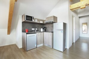 A compact kitchen with a microwave, coffee maker, and refrigerator.