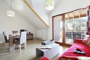 A modern living space with a dining area, a sofa, and a view of the outdoors.