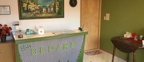 Una recepción con un diseño verde y blanco a cuadros, un reloj y un cuadro de un paisaje urbano en la pared.