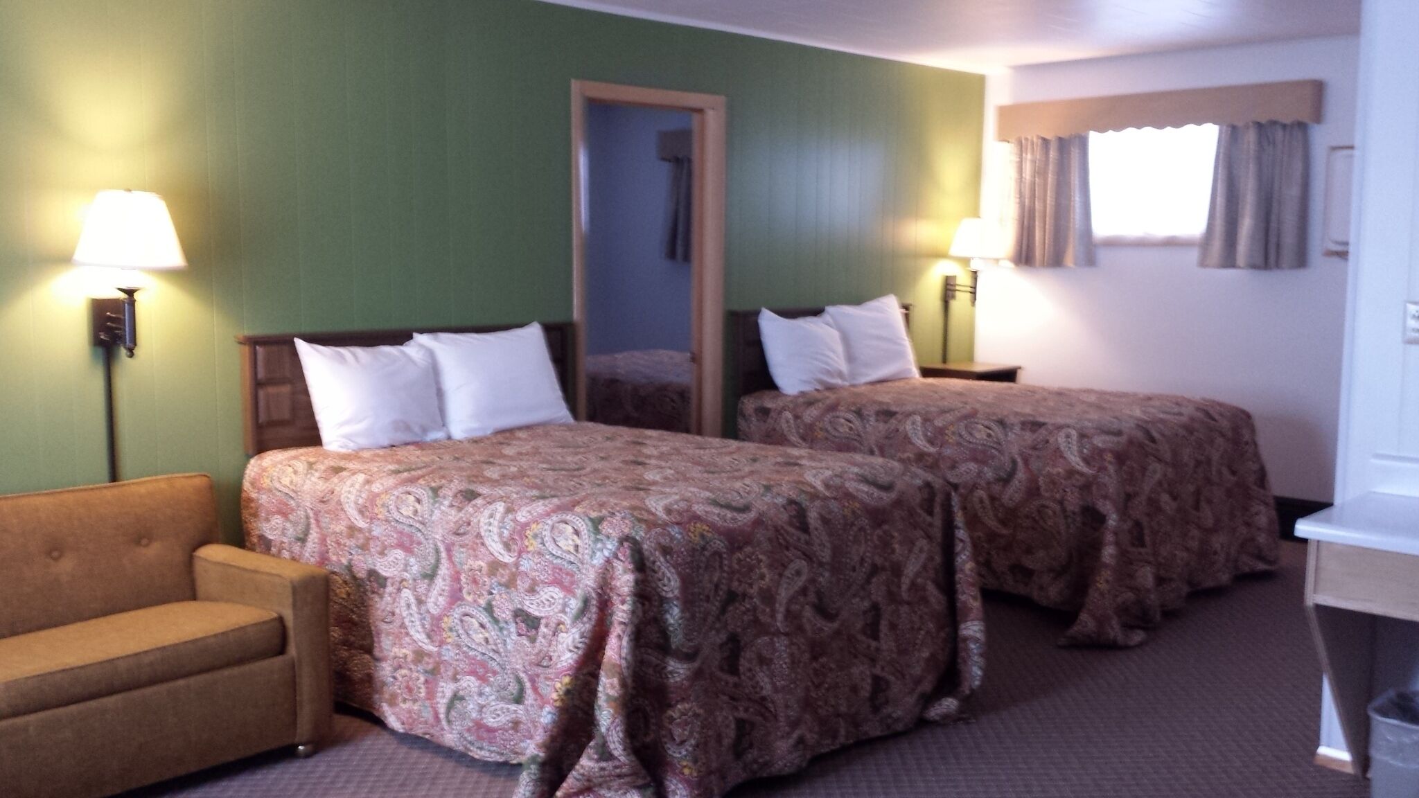 Una habitación de hotel con dos camas, un sofá, un escritorio y un espejo.