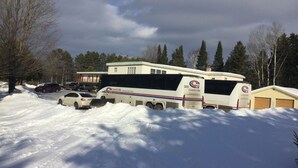Una caravana Coach USA estacionada en una zona nevada, con un edificio al fondo.