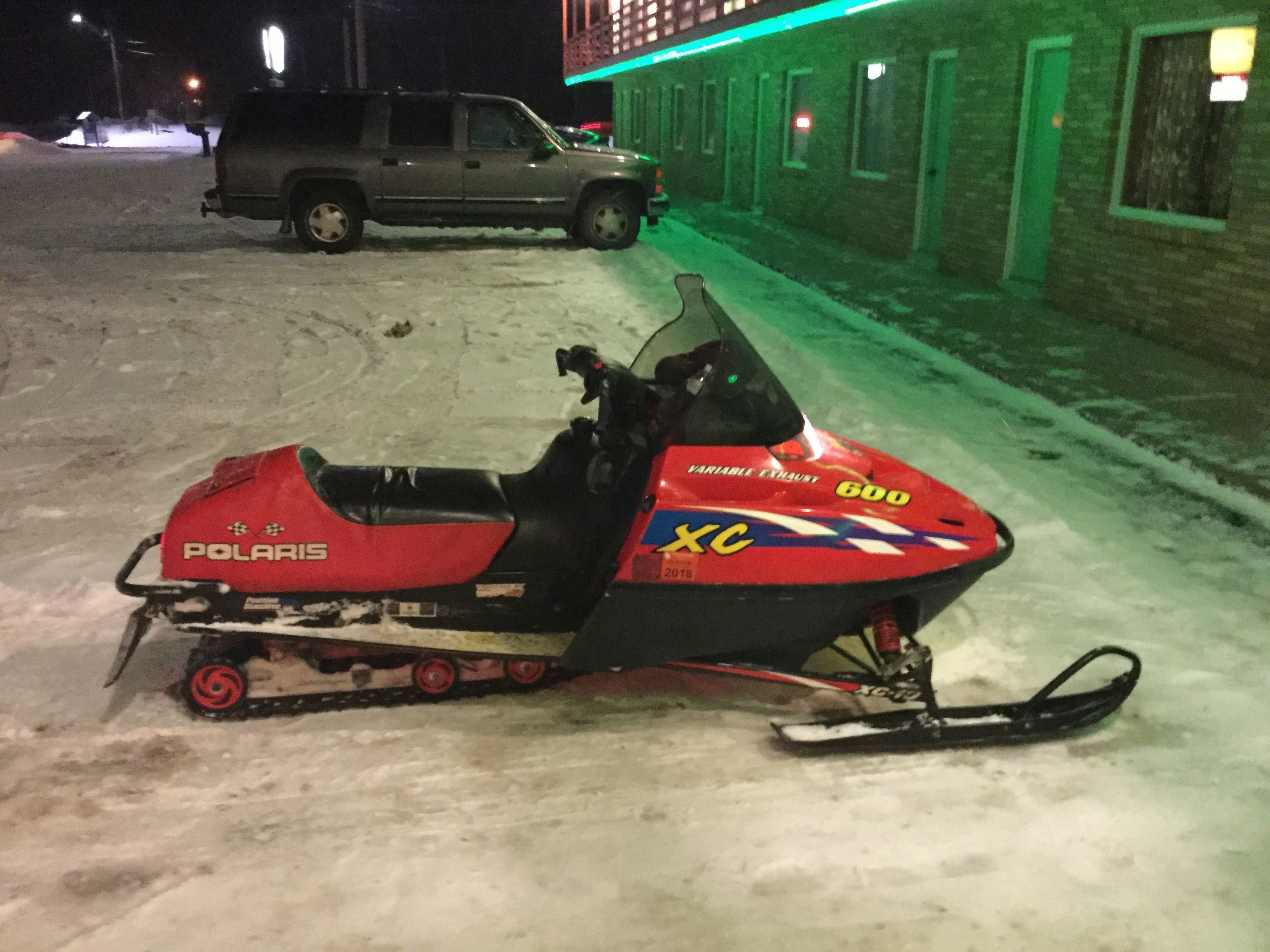 A snowmobile parked on a snowy surface with a building in the background.