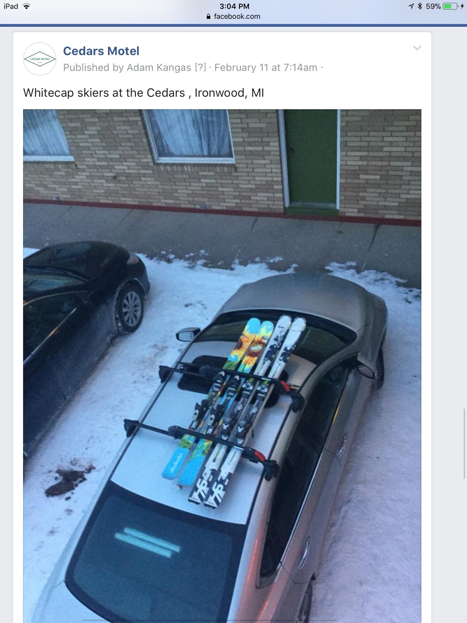 A car parked in a snowy area with skis mounted on the roof.