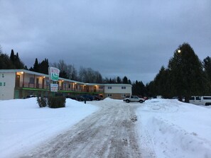 A motel with a signboard, a dirt road, and snow-covered surroundings. - Cedars Motel (Ironwood)
