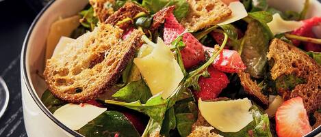 A bowl of salad with various ingredients and toasted bread pieces.