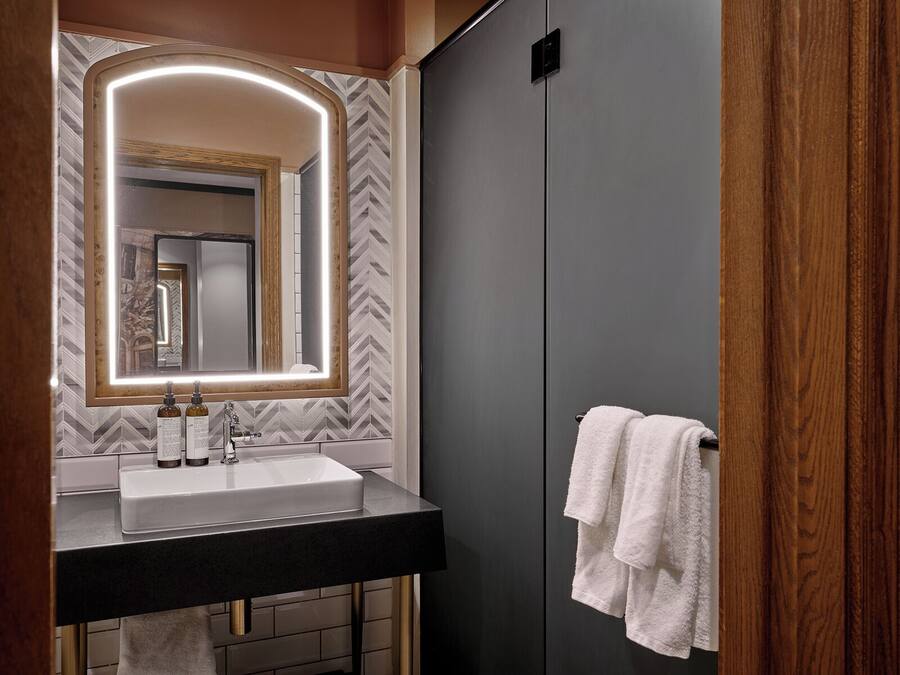 A modern bathroom with a large mirror, a sink, and a towel rack.