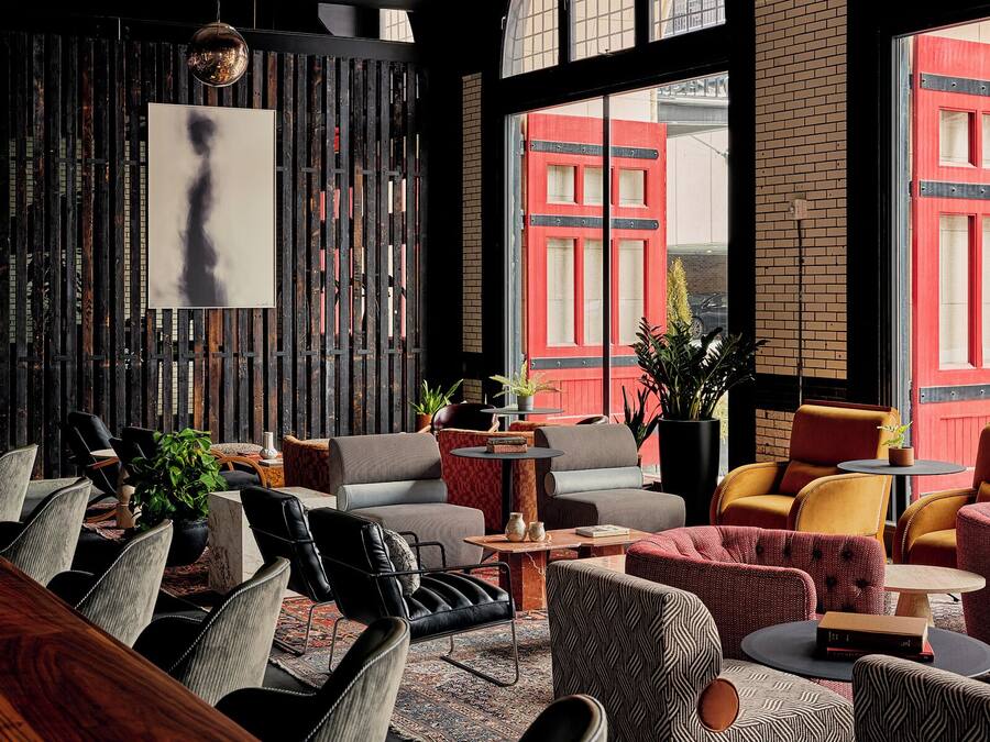 A modern lounge with leather chairs, a patterned rug, and a large window with a red building view.