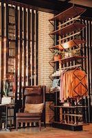 Un interior acogedor con pared de ladrillo, una silla de madera, estantería de metal con ropa y una planta en maceta.