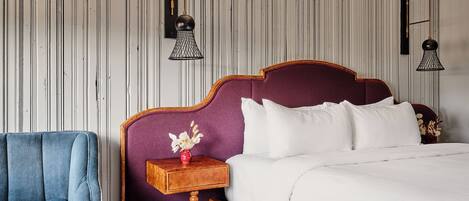 A bedroom with a bed, a nightstand, a chair, and two wall-mounted lamps.