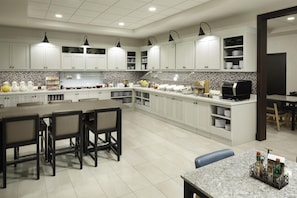 A modern kitchen with white cabinets, a granite countertop, and a dining area with a table and chairs.