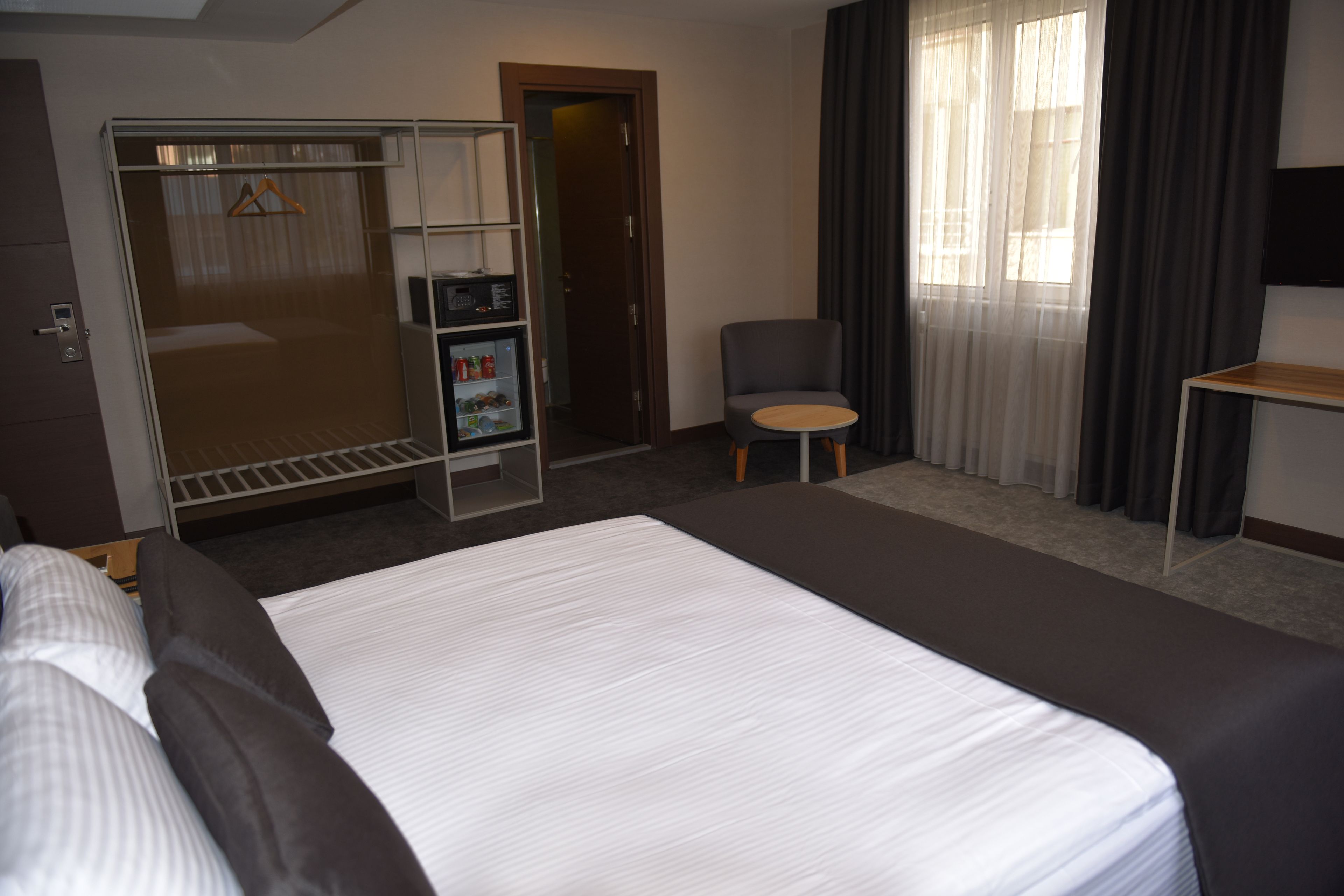 Una habitación de hotel con una cama grande, un escritorio, una silla, un armario y una mesita.