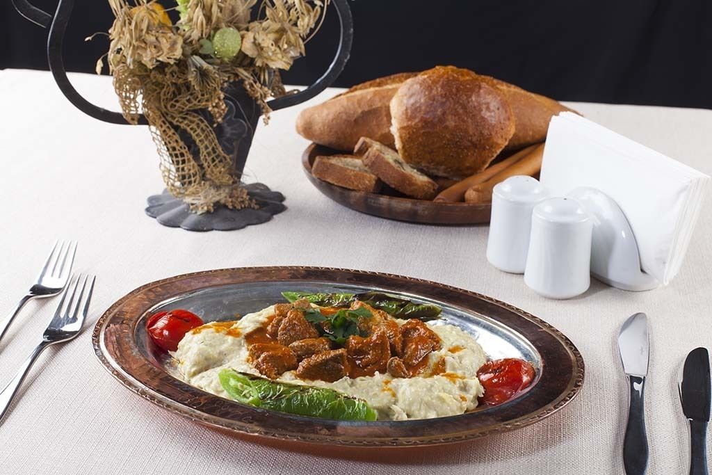 A plate of food with bread and salt shakers on a table.