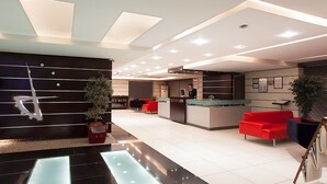 A modern hotel lobby with a reception desk, red seating, and potted plants. - Hotels Dalgiclar (Corum)