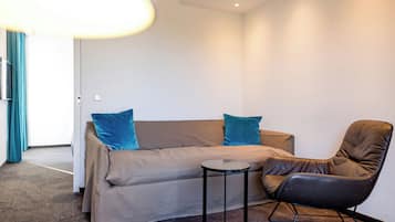 Ein modernes Zimmer mit einer Couch, zwei Kissen, einem kleinen Tisch und einem Ledersessel.