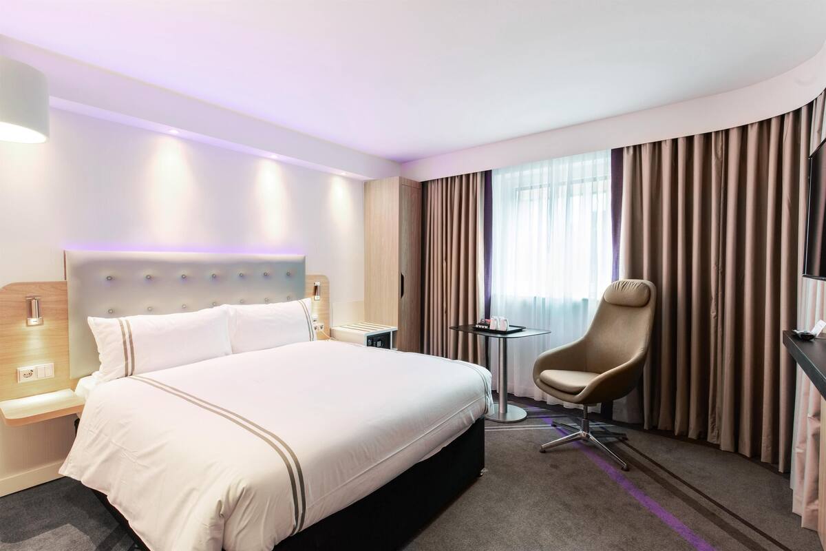 Une chambre d’hôtel avec un grand lit, un bureau, une chaise et un téléviseur.