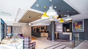 Un moderno vestíbulo de hotel con mostrador de recepción, zona de bar y asientos.
