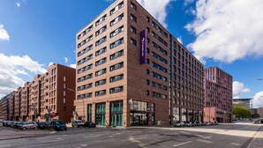 Un hotel de varios pisos con fachada de ladrillo, ventanas grandes y un llamativo cartel púrpura.