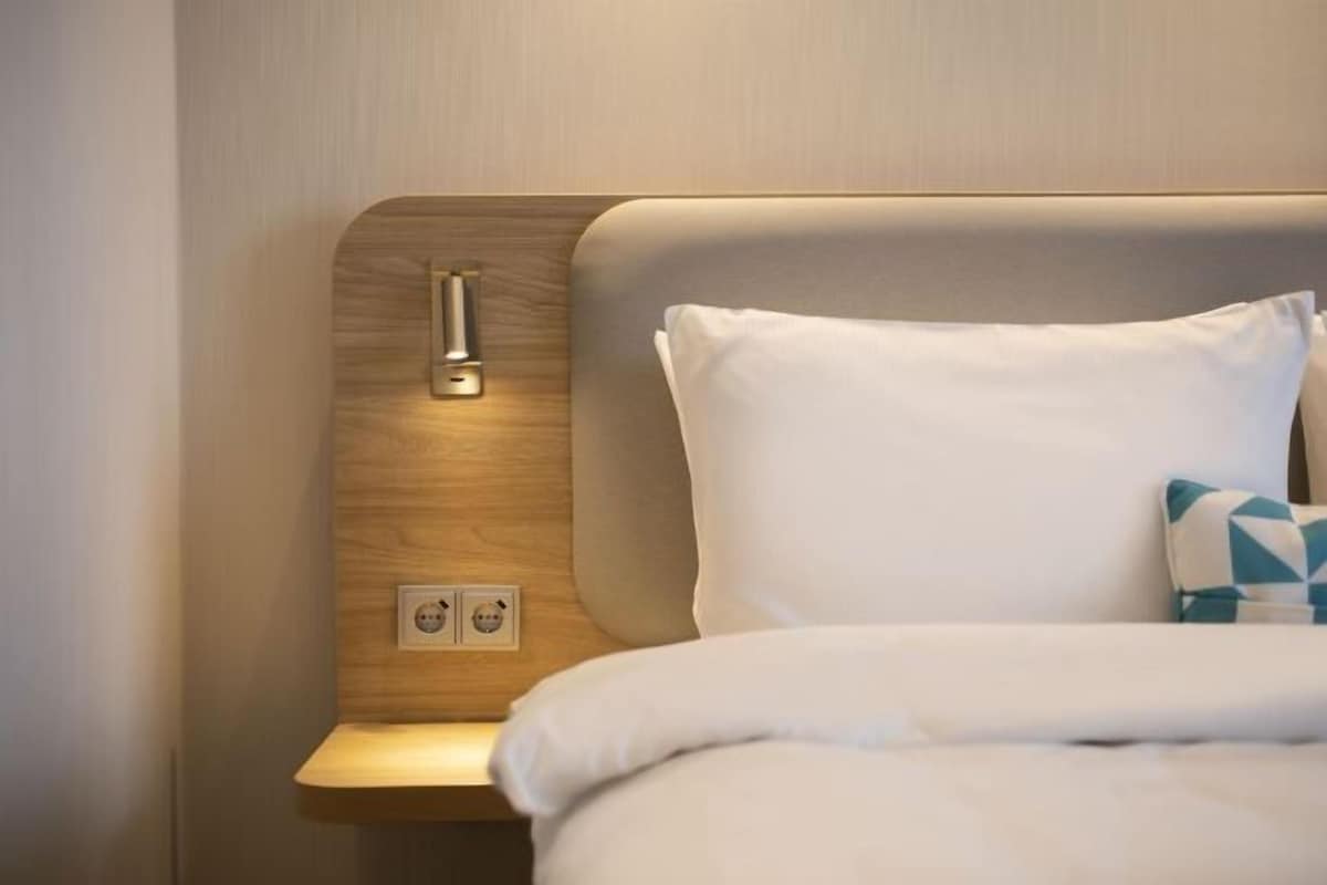 A hotel room with a bed, a bedside table, and a nightstand.