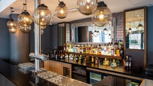 Zona de bar con mostrador pulido, una variedad de botellas de licor y un muro espejado.