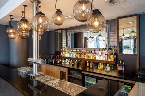 Eine Bar mit einer polierten Theke, einer Auswahl an Spirituosenflaschen und einer Spiegelwand.