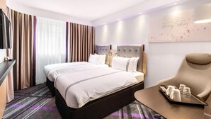 Una habitación de hotel con una cama grande, un escritorio, una silla y un adorno en la pared.