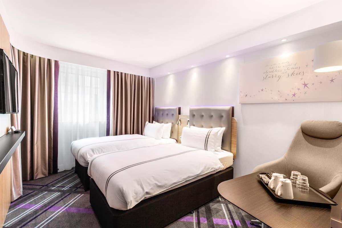 Une chambre d’hôtel avec un grand lit, un bureau, une chaise et un mur agrémenté d’un élément décoratif.